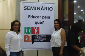 FOTO: Claudia Sampaio a esquerda ao centro um banner escrito - Seminário Educar para que? -  e ao lado direito Tatiane Vieira. 