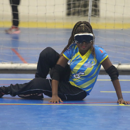 foto de uma atleta jogando GoalBall, sentada em uma quadra, vestida com o uniforme do ICB.
