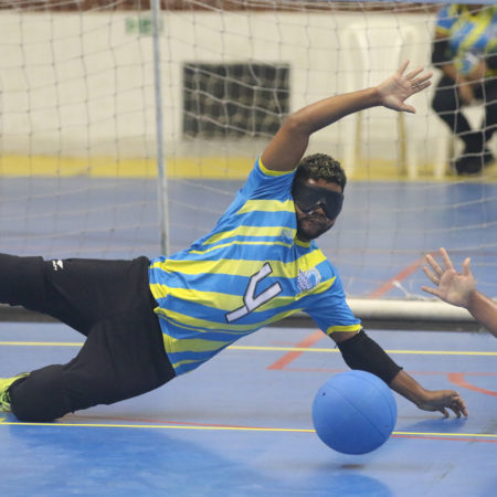 foto de um atleta jogando GoalBall, ele está em uma quadra, vestido com o uniforme do ICB.