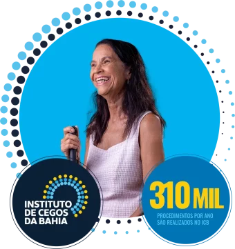 foto de uma senhora cega, com um vestido branco. Ela está de pé, sorrindo e segurando uma bengala.